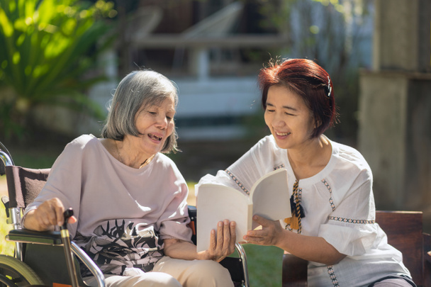 Starší pacienti a dcera, kteří společně čtou knihu, zlepšují paměť a pomáhají předcházet demenci. - Fotografie, Obrázek