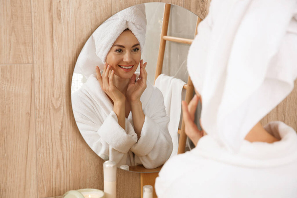 Beautiful woman wearing white bathrobe in front of mirror at home - Foto, Imagen