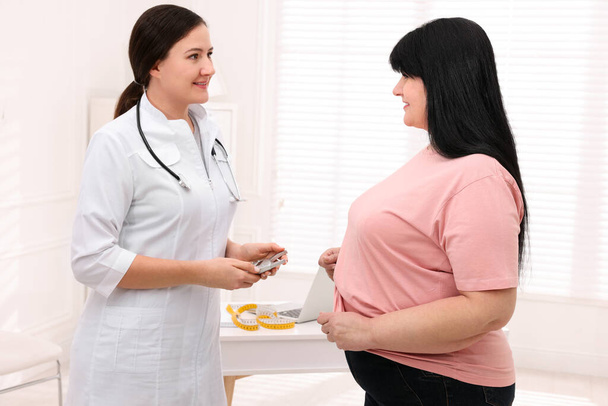 Overweight woman and nutritionist with digital caliper in clinic - Foto, afbeelding