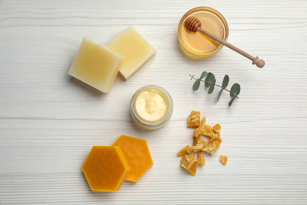 Natural beeswax, cream, honey and eucalyptus on white wooden table, flat lay - Фото, изображение