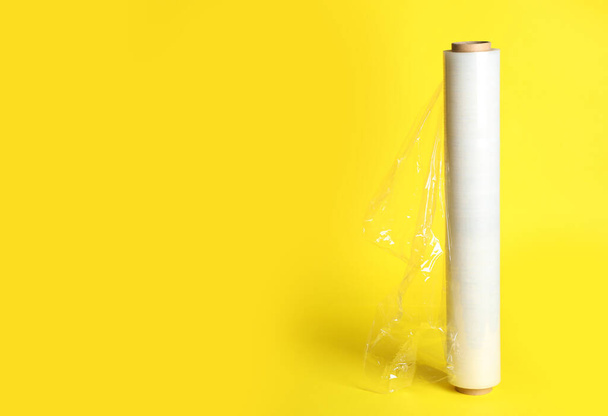 Roll of plastic stretch wrap film on yellow background, space for text - Zdjęcie, obraz