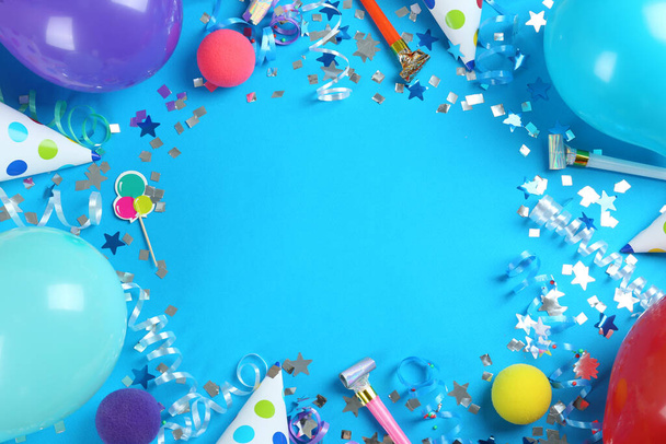 Frame of colorful serpentine streamers and other party accessories on light blue background, flat lay. Space for text - Foto, imagen