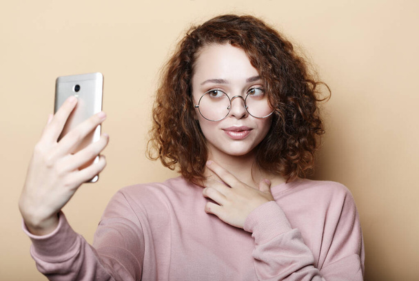 lifestyle, emotional and people concept: Young beautiful curly woman with smart phone - Photo, Image