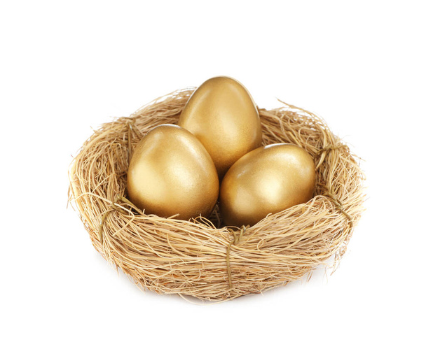 Shiny golden eggs in nest on white background - Foto, afbeelding