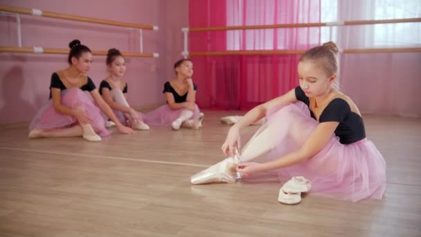 Viisi ballerina tytöt kauniita mekkoja istuu lattialla studio - Materiaali, video
