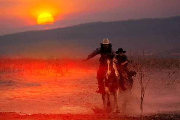 Silhouette di un cowboy che cavalca un cavallo che guadagna attraverso l'acqua al tramonto dietro una montagna. - Foto, immagini