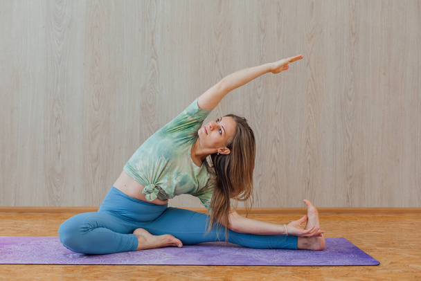 Young caucasian woman dressed in a blue leggins and t-shirt doing yoga asanas with yoga bricks at home. Fitness and healthy lifestyle concept. - Foto, imagen