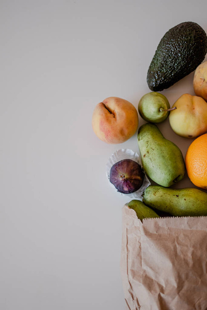 Une variété de fruits dans un sac en papier artisanal sont couchés sur la table. Pose plate saine avec espace de copie. Avocats, citrons, pêches, poires, oranges. - Photo, image