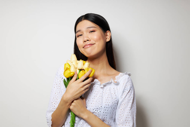 mujer con aspecto asiático en una camisa blanca flores primavera posando modelo de estudio inalterado - Foto, Imagen