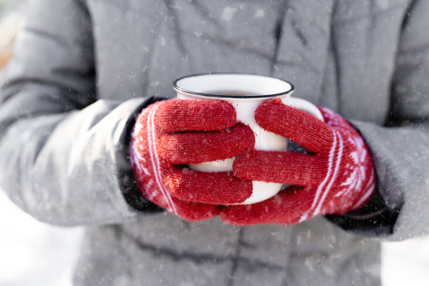 Hands in gloves holding cup - Φωτογραφία, εικόνα