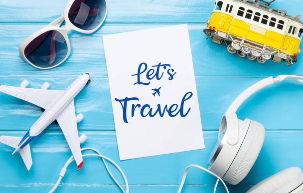 Reizen en vakantie concept. Reis accessoires en items. Vliegtuig- en tramspeelgoed, zonnebril en koptelefoon. Bovenaanzicht vlak lay - Foto, afbeelding