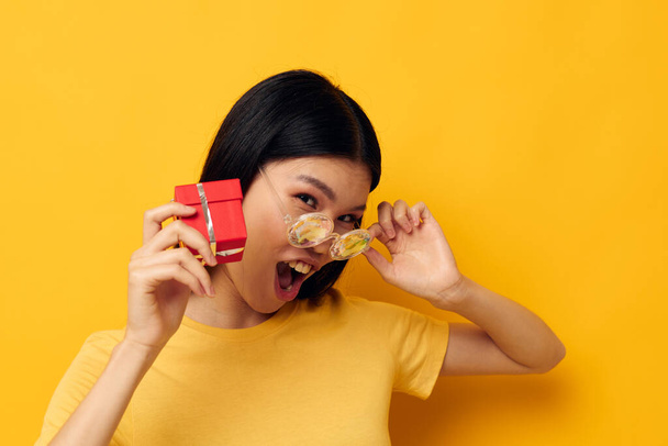 woman with Asian appearance with gift boxes in hands fun posing yellow background unaltered - Фото, зображення