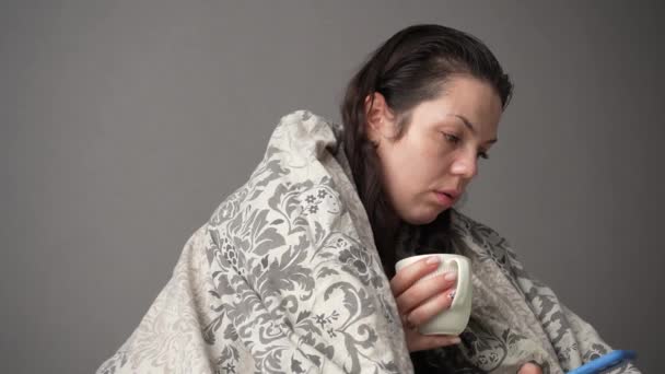Portrait d'une patiente malade et fatiguée avec une tasse blanche assise sur un canapé à la maison aux prises avec des symptômes du virus de la migraine buvant du thé chaud. - Séquence, vidéo