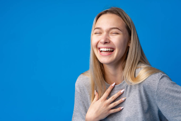 Happy smiling pretty teenage girl laughing over blue background - Foto, immagini