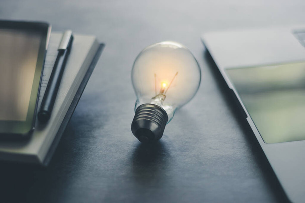Light bulb with book or text book and tablet and laptop with copy space. Business and education idea concept of learning inspiration and knowledge cognition. - Photo, Image