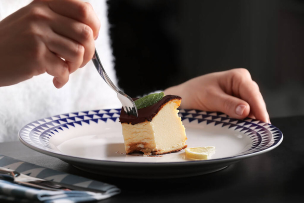 Nainen syö maukasta baskia palanut juustokakku pöydässä - Valokuva, kuva