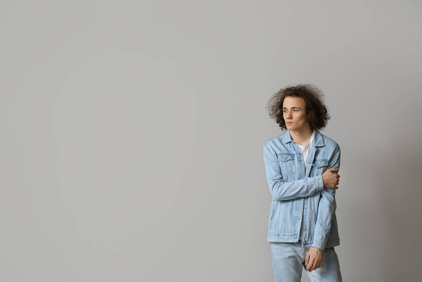 Модный молодой человек в стильной джинсовой одежде на светлом фоне - Фото, изображение