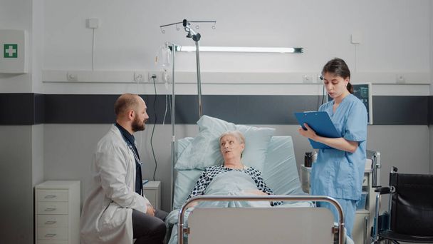 Ärzteteam berät alte Patientin im Bett - Foto, Bild