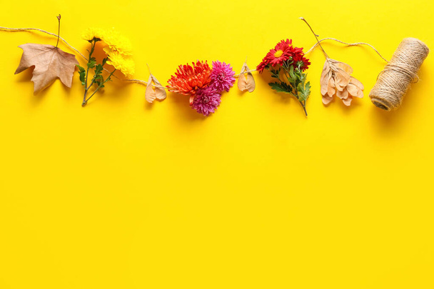 Composition with fresh chrysanthemum flowers and rope on yellow background - Фото, изображение