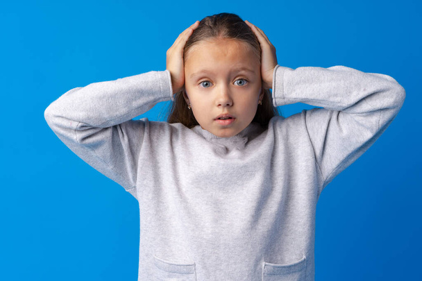 Shocked little girl looking with amazement on blue background - Foto, Bild