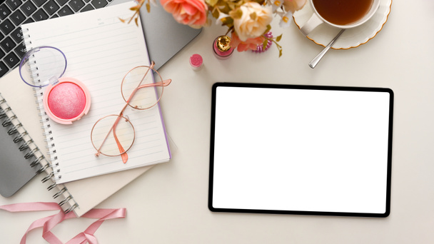 Spazio di lavoro femminile beauty blogger con laptop, fiori, tazzine da tè, trucco, notebook e tablet digitale bianco su sfondo bianco. vista dall'alto, posizione piatta - Foto, immagini