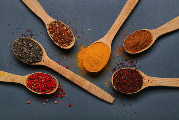 Wooden spoons with aromatic spices on dark background - Photo, Image