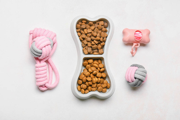 Комплект принадлежностей для ухода за животными и миска с продуктами питания на светлом фоне - Фото, изображение