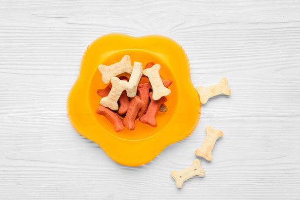 Bowl of tasty snacks for pet on white wooden background - Foto, imagen