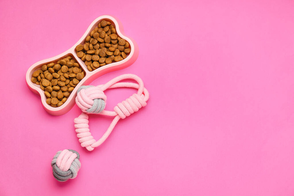 Bowl kuivalla lemmikkieläinten ruokaa ja leluja värillinen tausta - Valokuva, kuva