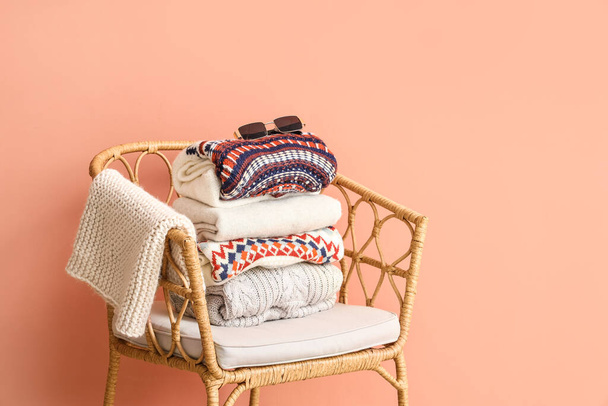 Wiklinowe krzesło z stosem dzianych swetrów na tle koloru - Zdjęcie, obraz