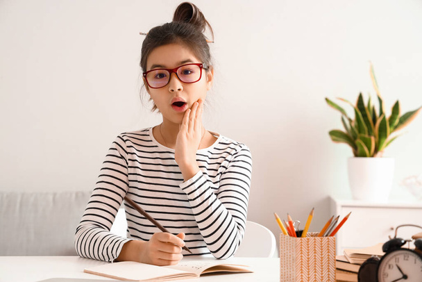 Shocked little Asian girl studying with online tutor at home - Foto, Imagem