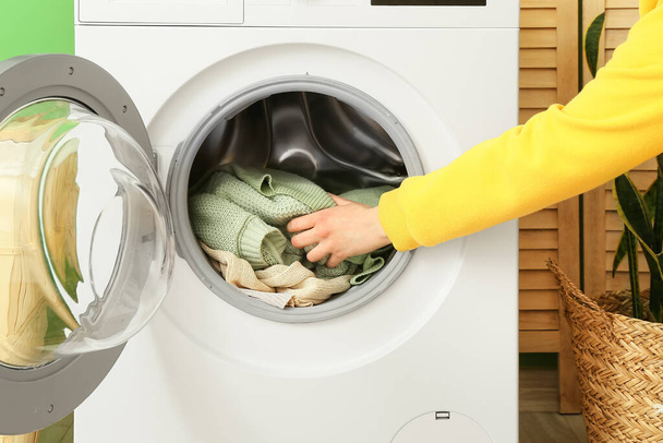 Egy nő piszkos ruhákat tesz a mosógépbe. - Fotó, kép