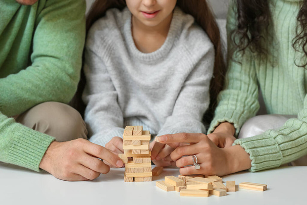 Happy family in warm sweaters playing jenga game at home, closeup - Фото, изображение