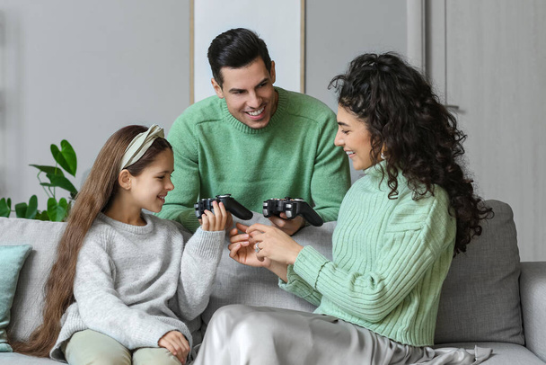 Gelukkige familie in warme truien met game pads thuis - Foto, afbeelding