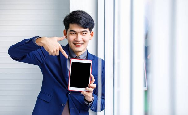 Millennial Aziatische knappe slimme zelfverzekerde professionele succes mannelijke manager zakenman ondernemer in formele blauwe pak glimlachen holding smartphone staan in de buurt van wolkenkrabber kantoor venster - Foto, afbeelding