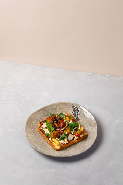 Bruschetta with octopus, vegetables and sauce on gray ceramic plate. Toast with octopus in contemporary style. Chef concept bruschetta in modern ceramic dishware. Handmade dinner plate - Foto, Imagen