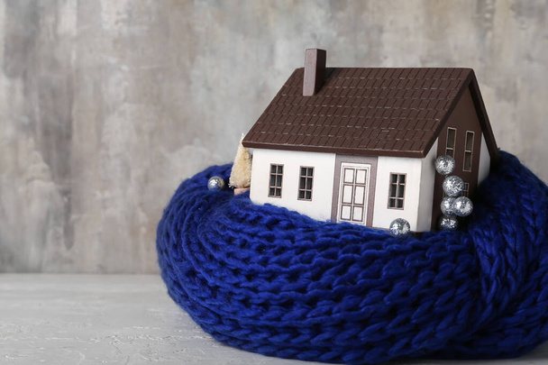 Домашняя модель с шарфом и декором на столе на фоне решетки. Концепция нагрева - Фото, изображение