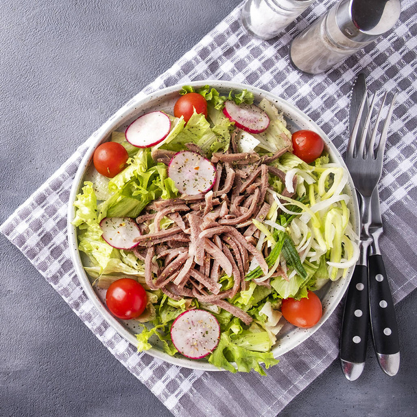 Delicious beef tongue salad served with fork and knife. Top view - Photo, Image