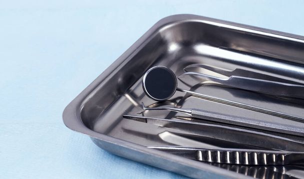 Metal tray with medical instruments, dental equipment, on a blue background, horizontal, no people, selective focus, - Photo, image