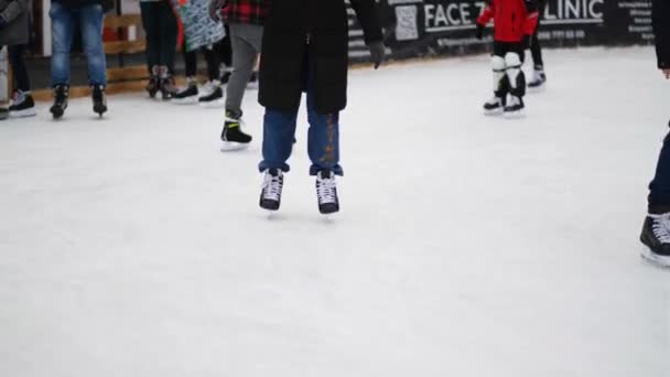 Artistik patinaja yakın çekim. Kışın buz pateni pisti. İnsanlar paten kayıyor. Patenler buzda kayar. Buz pateni kış sporu ve eğlencedir. Kadınlar, çocuklar, erkek bacakları gider. Noel zamanı. - Video, Çekim
