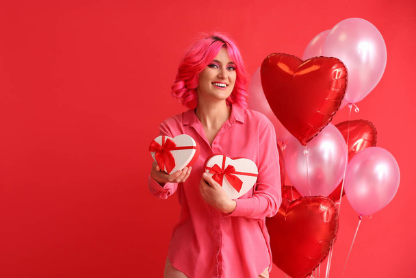 Κομψή γυναίκα με φωτεινά μαλλιά, δώρα και μπαλόνια αέρα στο φόντο χρώμα. Γιορτή του Αγίου Βαλεντίνου - Φωτογραφία, εικόνα