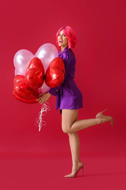 Glückliche Frau mit hellen Haaren und Luftballons auf farbigem Hintergrund. Valentinstag-Feier - Foto, Bild