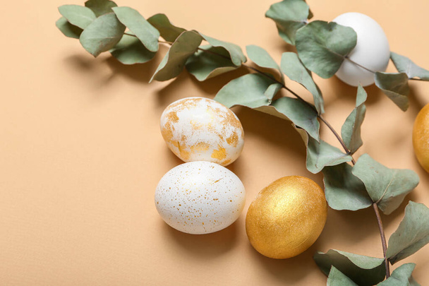 Красивые пасхальные яйца с эвкалиптовыми ветвями на цветном фоне, крупным планом - Фото, изображение