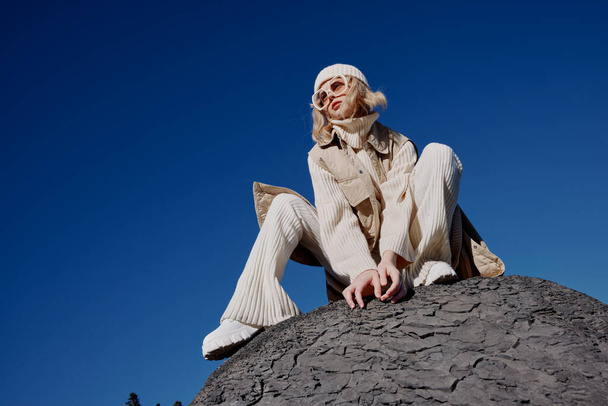 mujer en ropa de otoño se encuentra en un paisaje de roca azul cielo paisaje - Foto, imagen