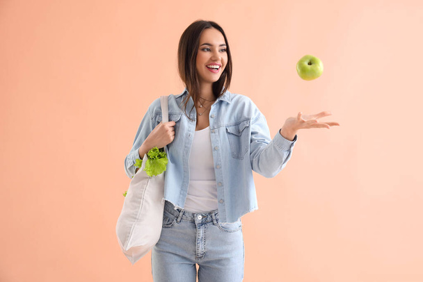 Jeune femme avec sac écologique et pomme sur fond beige - Photo, image