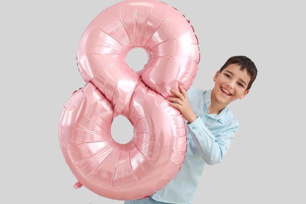 Niño pequeño con globo grande en forma de figura 8 sobre fondo claro. Día Internacional de la Mujer - Foto, imagen