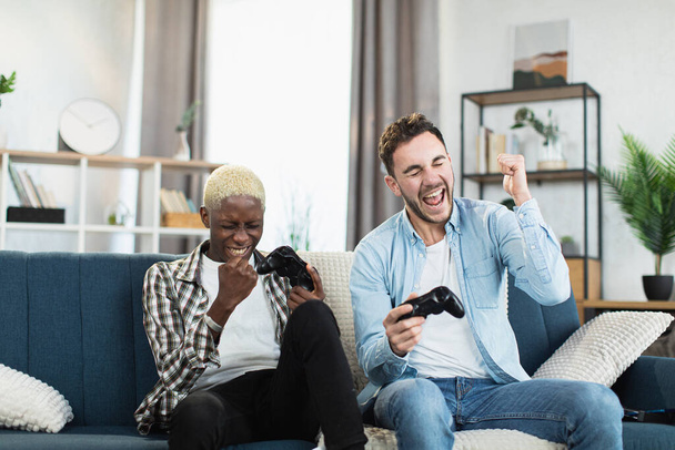 Cheerful gay couple enjoying victory in video games - Foto, immagini