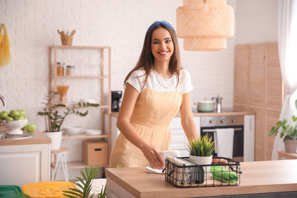 Mujer joven limpiando mesa con servilleta en la cocina - Foto, Imagen