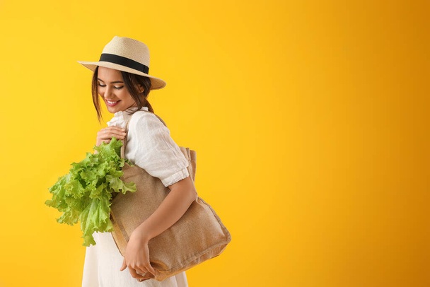 Junge Frau mit Ökotasche und Salat auf gelbem Hintergrund - Foto, Bild