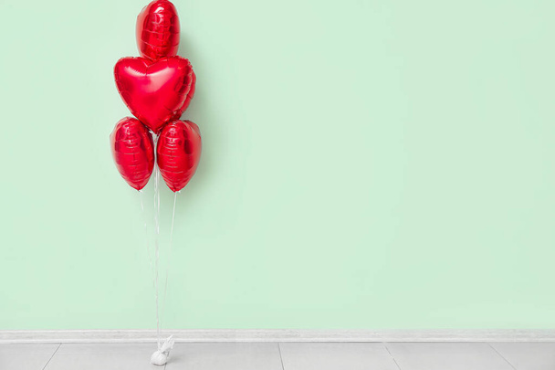 Beautiful heart-shaped balloons for Valentine's Day celebration near color wall in room - Photo, Image